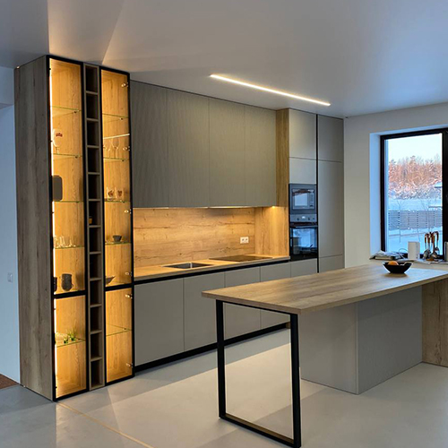 Дизайн кухни центрируется вокруг просторного острова, который служит одновременно и рабочей зоной, и барной стойкой, дополняясь изящной витриной для посуды.